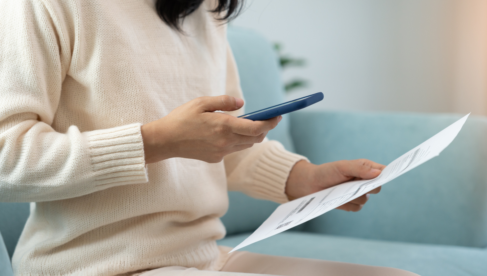 woman holding a phone and an invoice